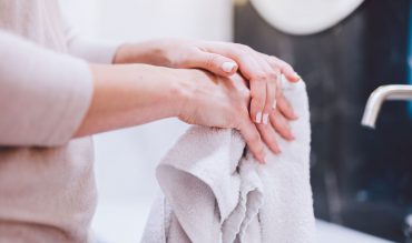 woman-wiping-hands-in-towel-after-washing-them-hyg-22ZGBH4.jpg